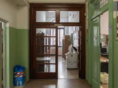 ...proseguendo a sinistra su un corridoio dove vi sono ancora le originali porte in legno, sovrastate da targhette dorate